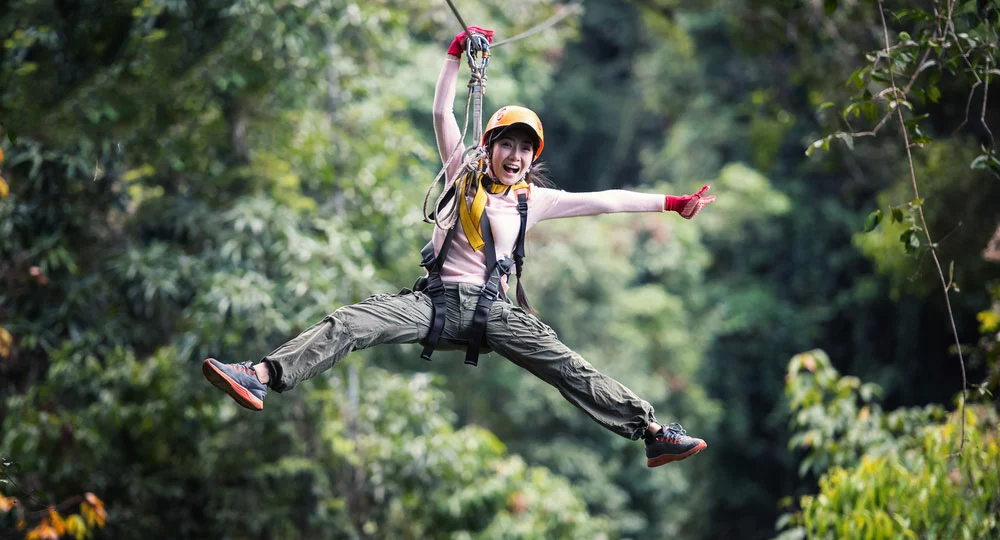 young woman ziplining through the trees in the Smoky Mountains