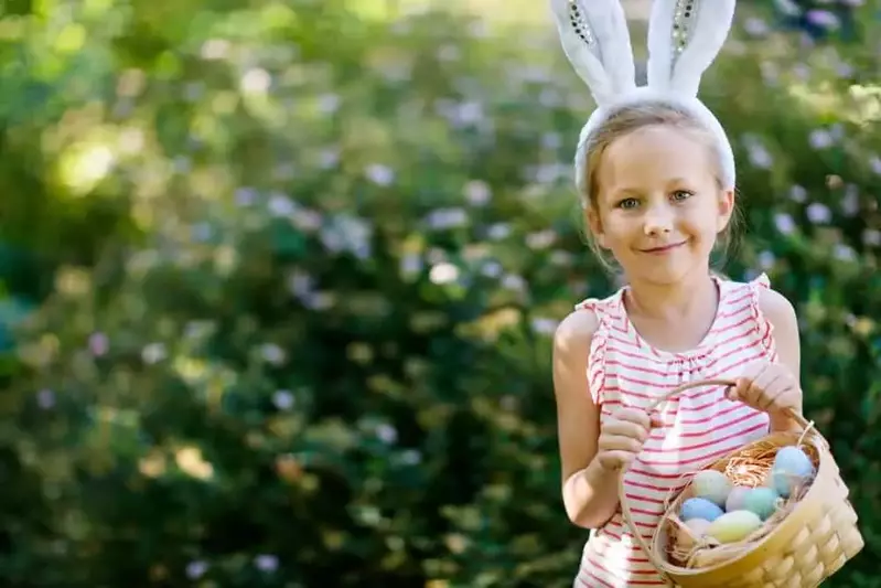 young girl wearing bunny ears carrying Easter basket filled with colorful eggs