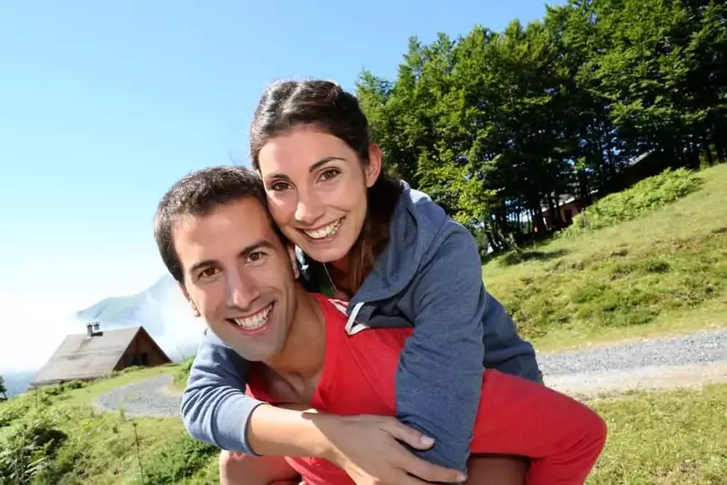 a man giving his wife a piggy back ride in front of a Smoky Mountain cabin