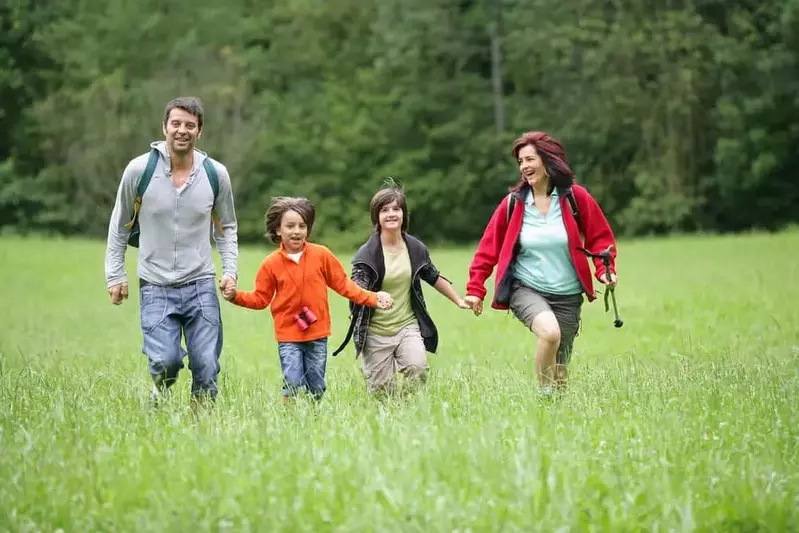 Family running through field holding hands in the Smoky Mountains