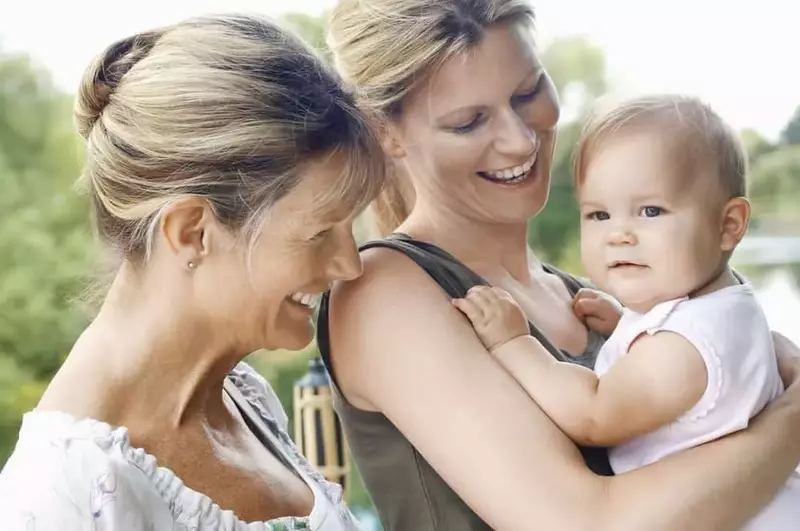 Grandmother smiling at mother holding baby