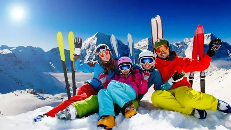 Family sitting in snow with skis