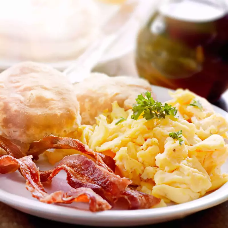 delicious scrambled eggs with bacon and a biscuit