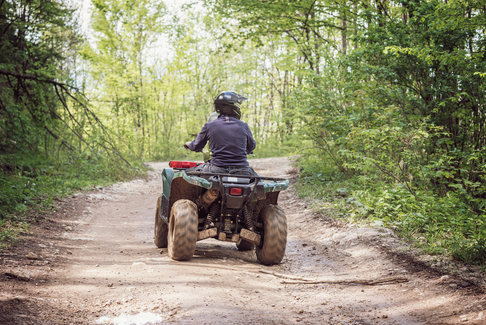 riding ATV on dirt trail in woods