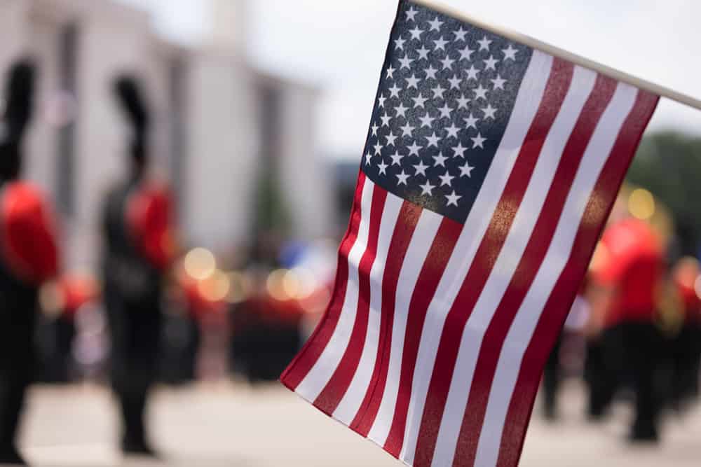 American flag in front of a blurred parade for Independence Day