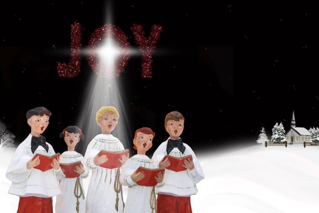 Image of Christmas Carolers near a church with the word Joy in the background