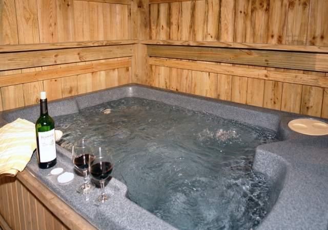 Glasses of wine sitting next to a hot tub in a Gatlinburg cabin