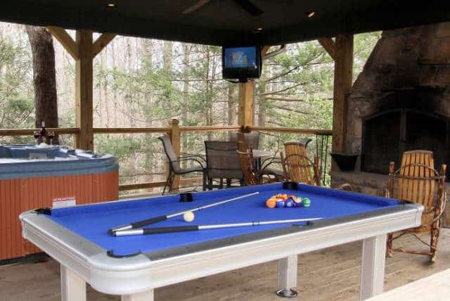 the deck of a Gatlinburg cabin with fireplace pool table and rocking chairs