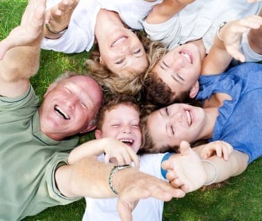 Happy family lying in a circle in the park and raising their hands