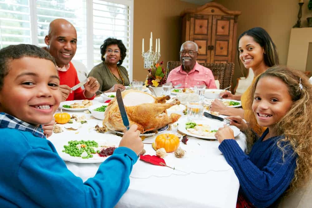 Family at Thanksgiving table eating turkey
