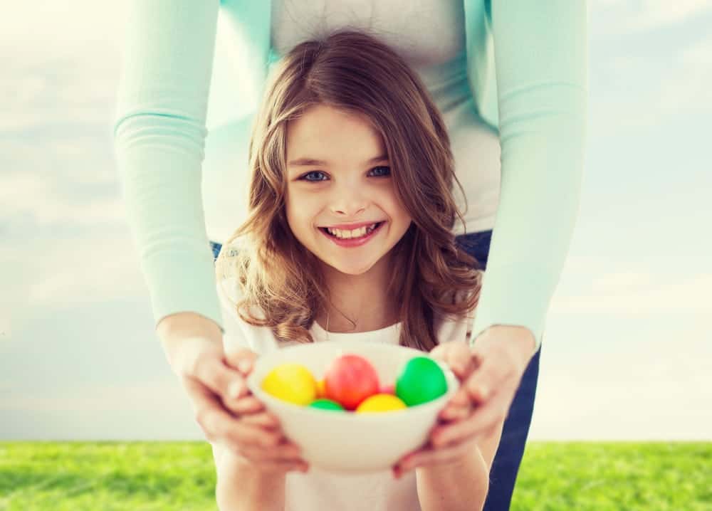 Daughter and mother holding a bowl of colorful Easter eggs
