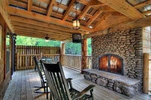 beautiful stone fireplace on cabin deck with rocking chairs