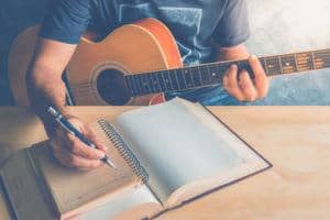 boy writing a song while holding guitar